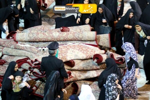 تلاش بانوان برای جمع آوری فرش های حرم رضوی در پی بارش شدید باران