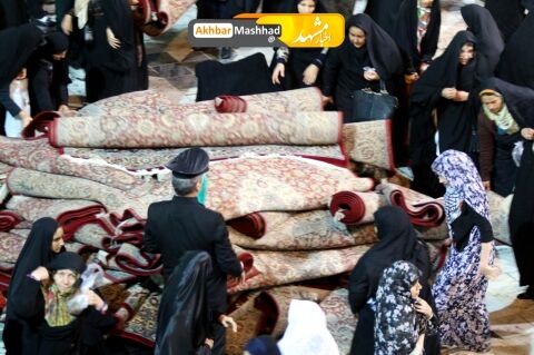 تلاش بانوان برای جمع آوری فرش های حرم رضوی در پی بارش شدید باران