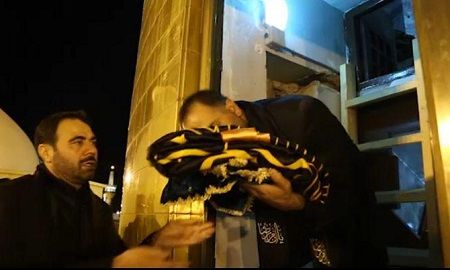 لحظه باز کردن درب گنبد حرم مطهر رضوی برای حمل و نصب پرچم عزای حسینی